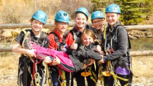 Group of girls in climbing gear holding a girl